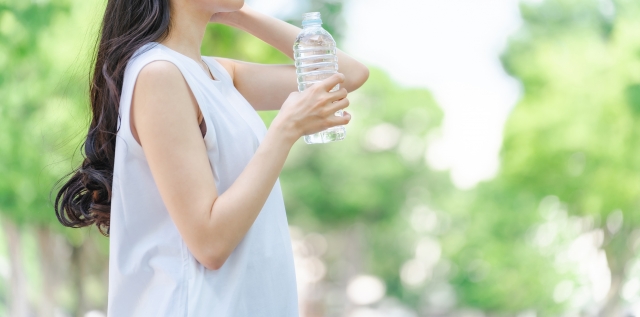 自然の中でペットボトルの水を飲もうとしている女性の写真